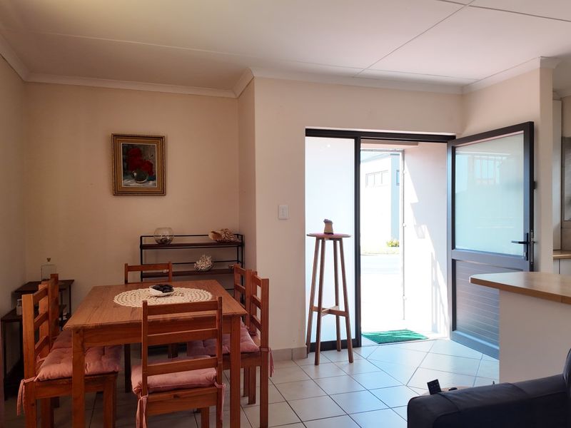 Open plan living and dining area featuring tiled flooring, neutral walls, and direct access to the exterior through an aluminium framed door.