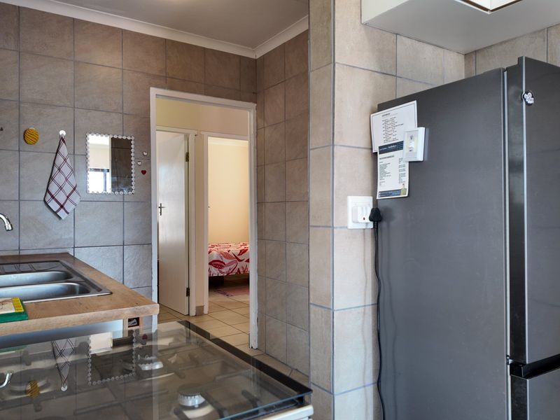 A functional kitchen area featuring tiled walls, a double bowl stainless steel sink, and a built-in gas hob with wooden countertops.