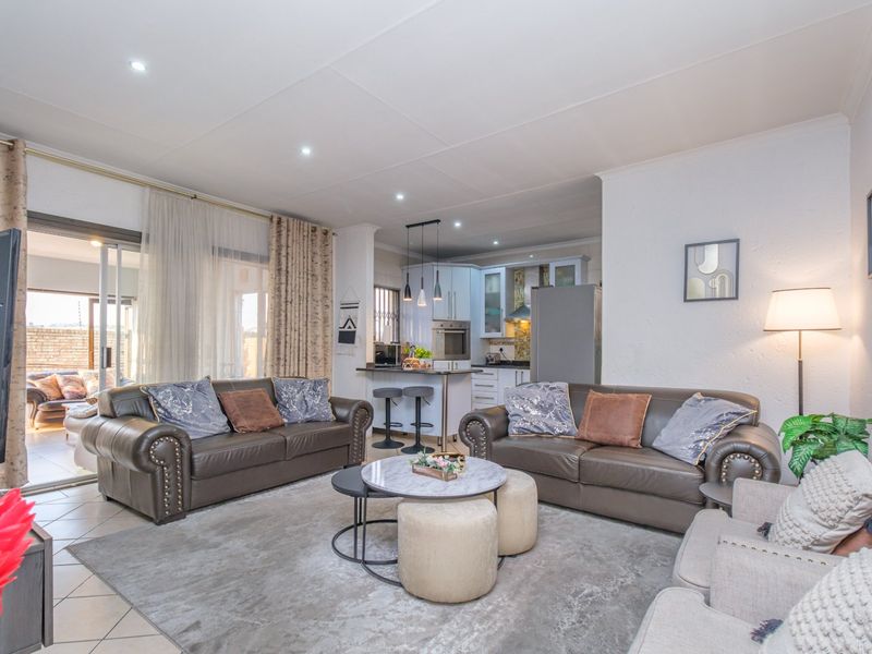 Spacious open-plan living area featuring a modern kitchen with built-in appliances and seamless access to an outdoor patio through sliding glass doors.