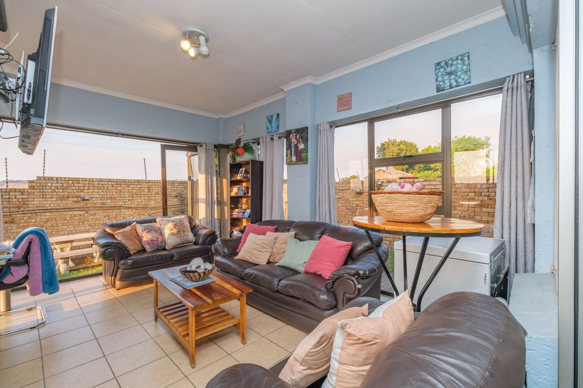 A bright living room featuring large aluminium sliding doors and windows that provide ample natural light and views of the rear garden area.