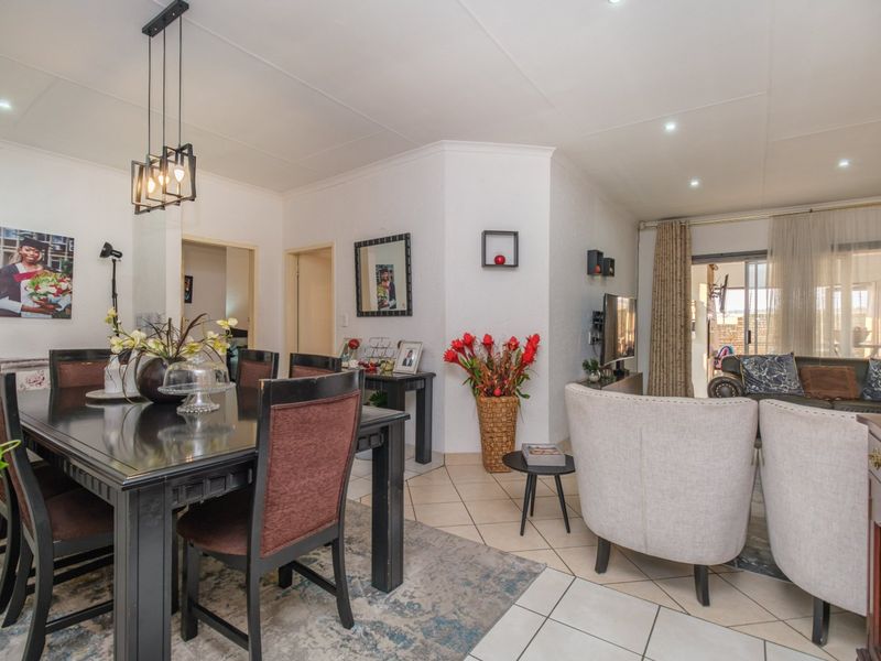 An open-plan living and dining area featuring tiled flooring, recessed lighting, and a sliding glass door leading to an outdoor space.