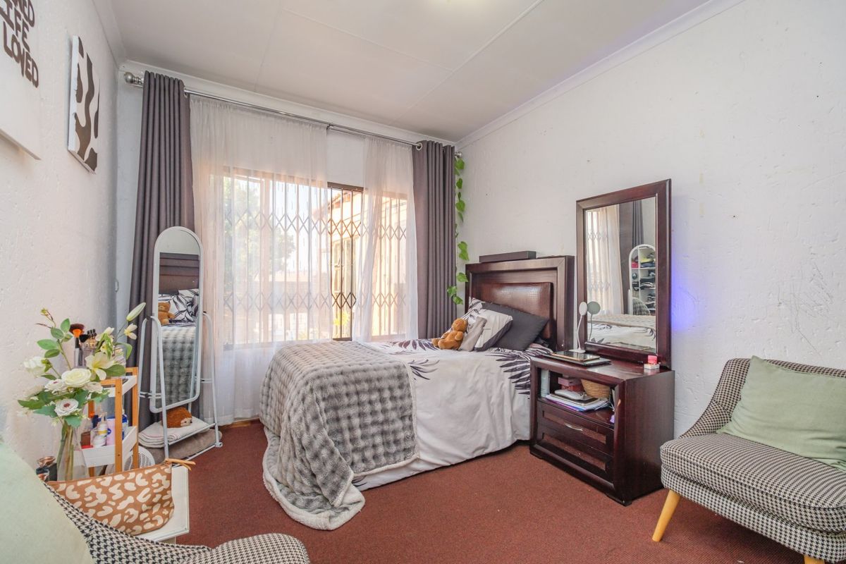 A bedroom featuring carpeted flooring, a security gate on the window, and curtain rails.