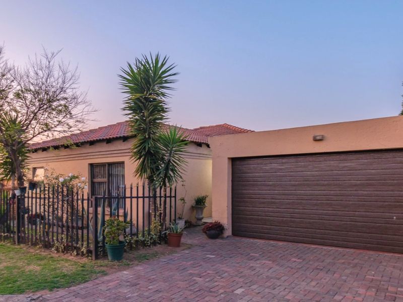 Front view of the property featuring a paved driveway, secure metal fencing, and an integrated garage with a tiled roof.