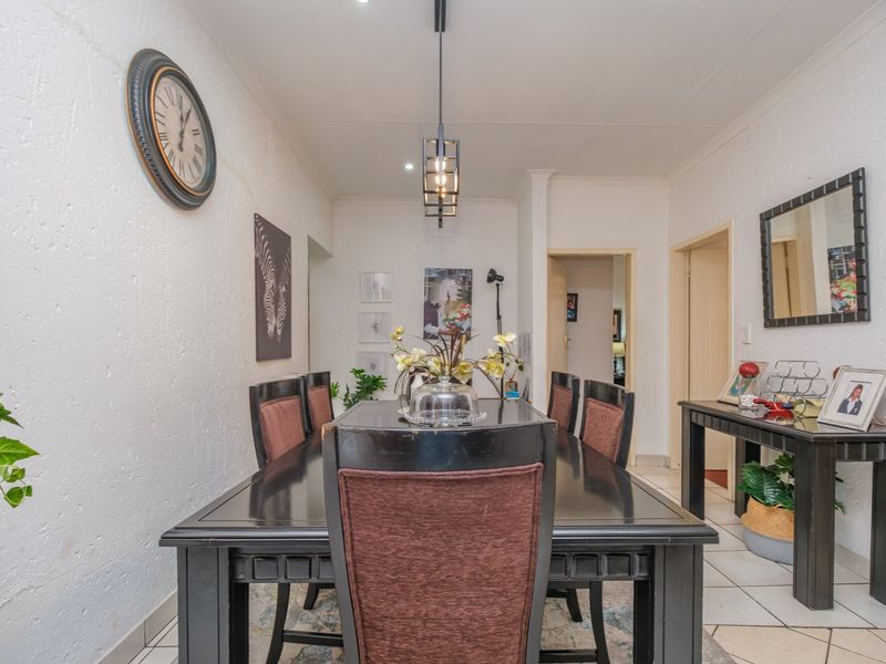 A dining room featuring tiled flooring, textured walls, and a central pendant light fixture, providing a functional space for family meals.