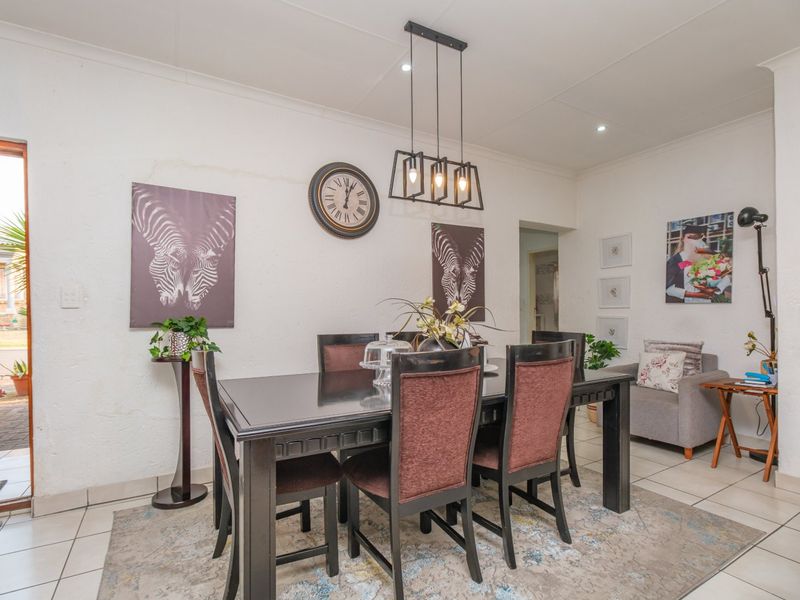 A dining room featuring tiled flooring, recessed downlighting, and a modern pendant light fixture, with direct access to an exterior area.