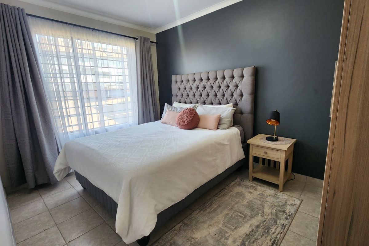A well-maintained bedroom featuring neutral tiled flooring and a dark grey accent wall, providing a clean and modern aesthetic.