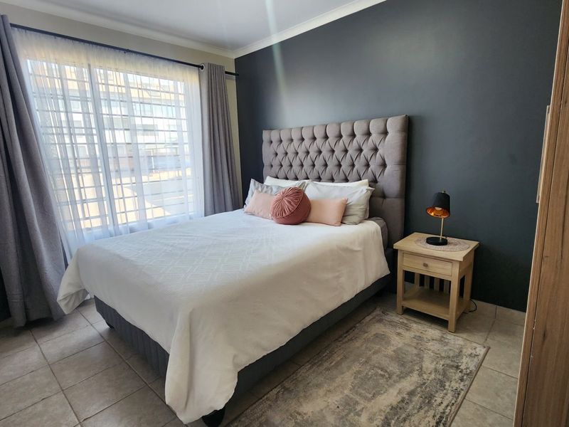 A well-maintained bedroom featuring neutral tiled flooring and a dark grey accent wall, providing a clean and modern aesthetic.