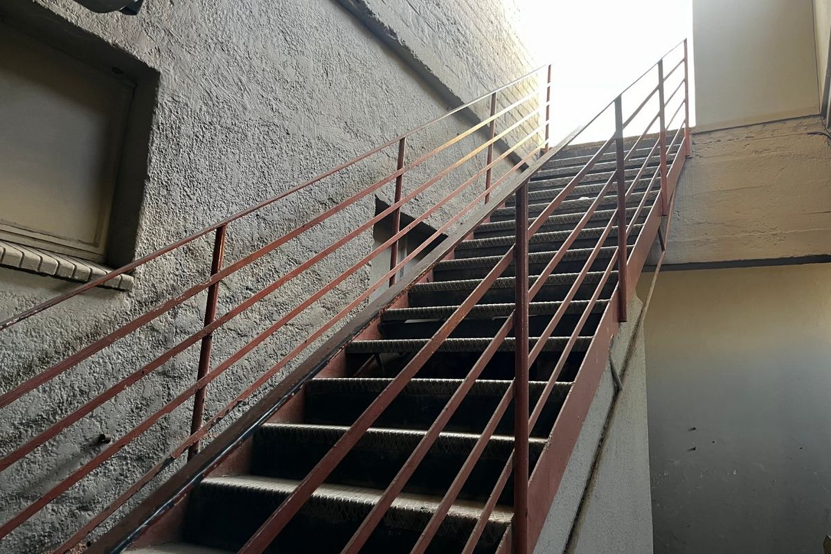 An exterior metal staircase providing access to an upper level, featuring a weathered finish and industrial design.