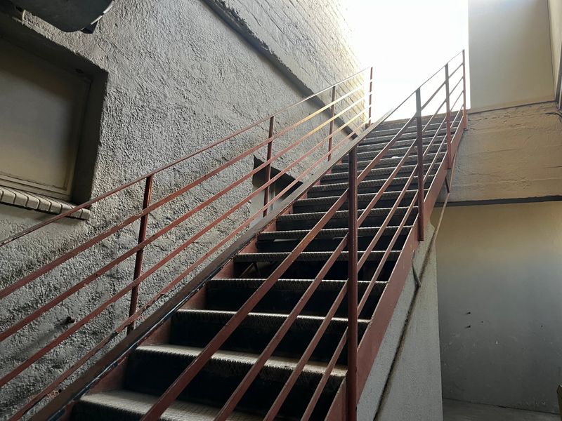 An exterior metal staircase providing access to an upper level, featuring a weathered finish and industrial design.