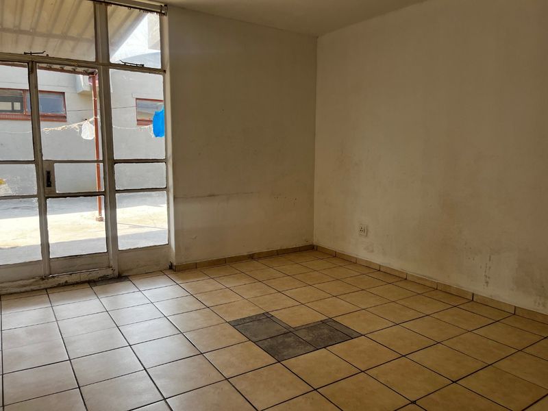 An empty living room featuring tiled flooring and a large glass door providing access to the exterior area.