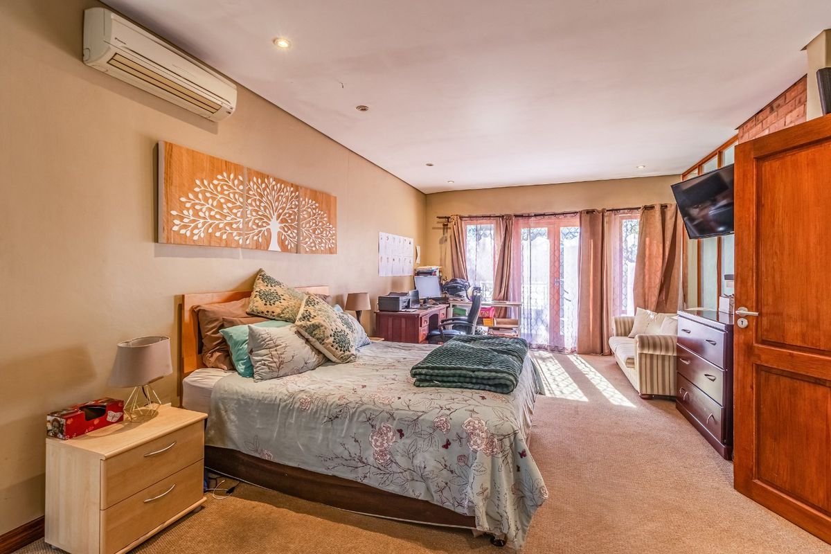 Spacious bedroom featuring carpeted flooring, recessed lighting, a wall-mounted air conditioning unit, and direct access to an outdoor area through sliding glass doors.