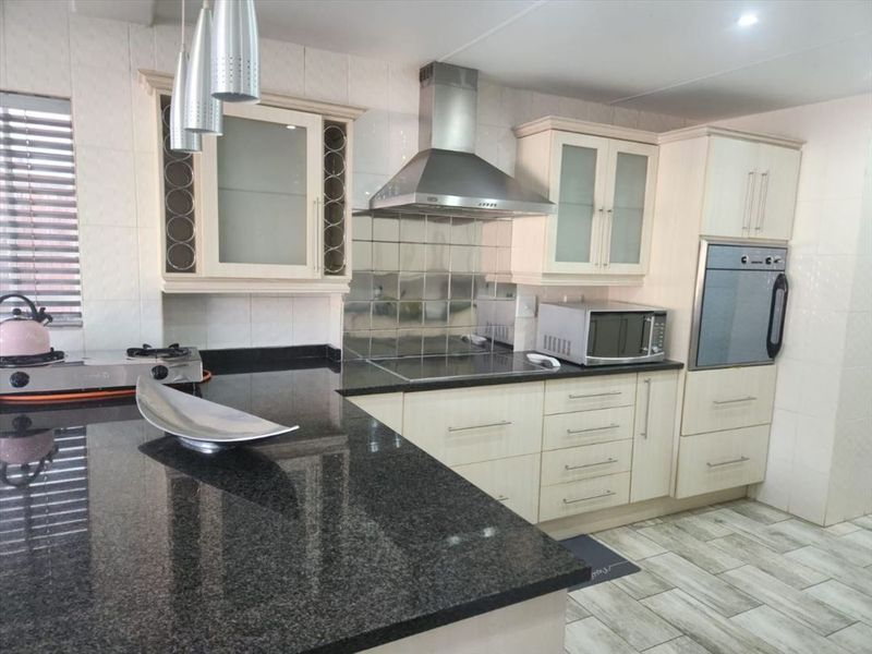 A well-maintained kitchen featuring granite countertops, built-in oven, extractor fan, and ample fitted cabinetry with glass-fronted display units.