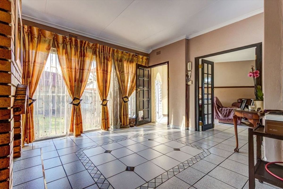 Spacious living area featuring tiled flooring, a brick fireplace, and direct access to the exterior through sliding glass doors.