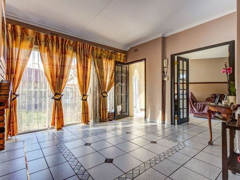 Spacious living area featuring tiled flooring, a brick fireplace, and direct access to the exterior through sliding glass doors.
