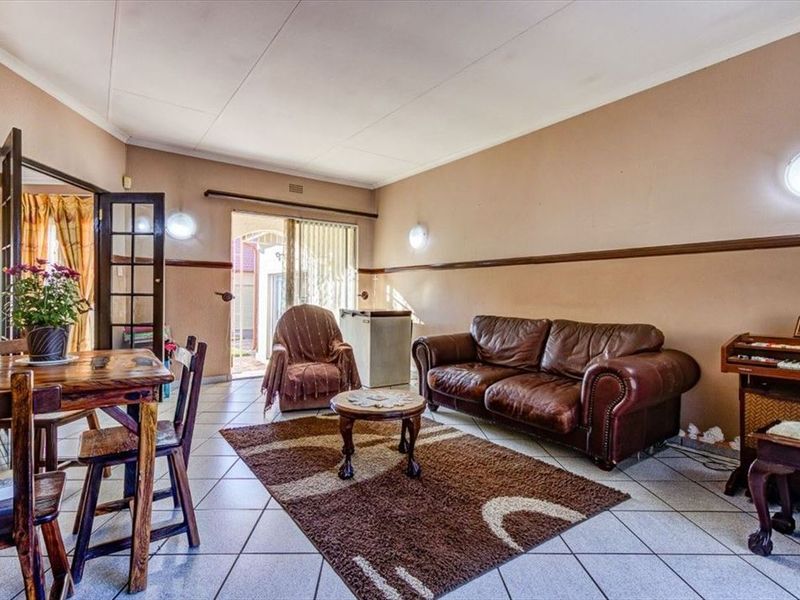 Spacious living area featuring tiled flooring, wall-mounted lighting, and direct access to the outdoor patio through sliding glass doors.