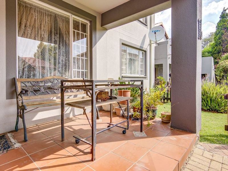 A covered outdoor patio area featuring tiled flooring, providing a functional space for relaxation overlooking the garden.