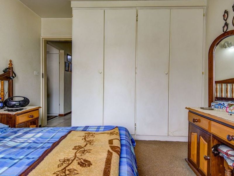 A bedroom featuring built-in cupboards and carpeted flooring, providing functional storage space within the room.