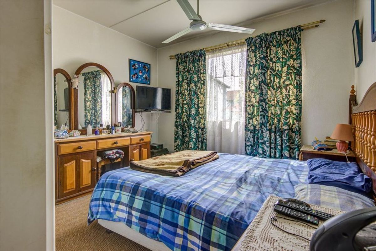A functional bedroom featuring carpet flooring and a ceiling fan, offering a comfortable space with natural light.