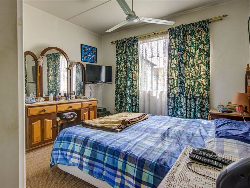A functional bedroom featuring carpet flooring and a ceiling fan, offering a comfortable space with natural light.