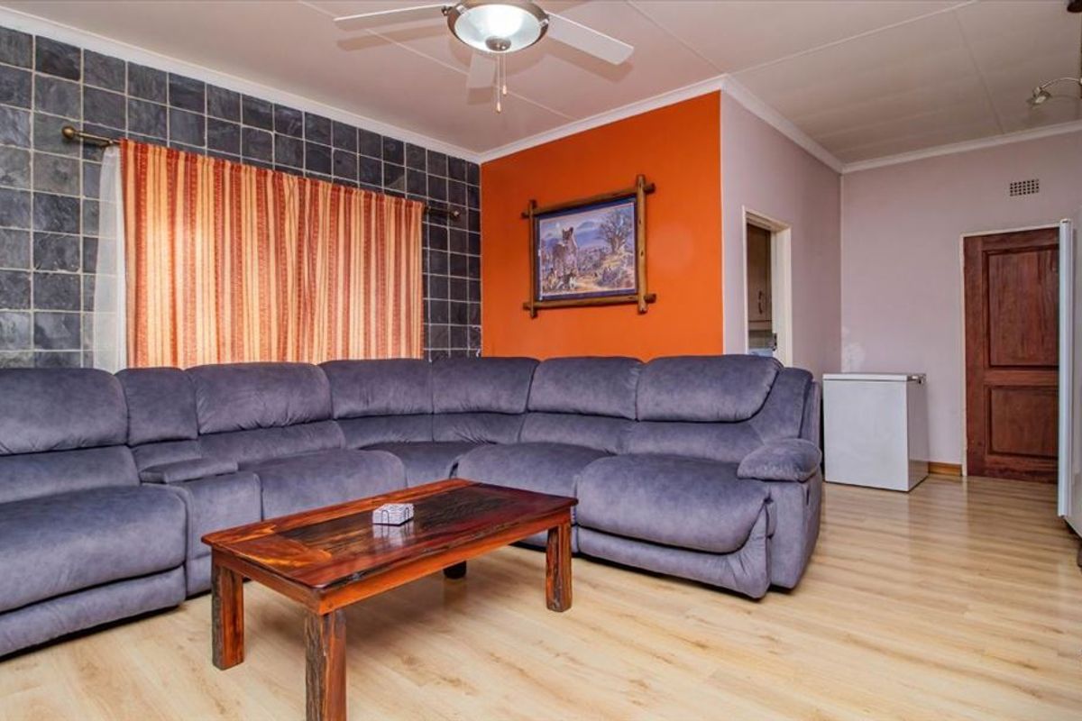 A living room featuring laminate flooring, a slate tile accent wall, and a ceiling fan, providing a functional and comfortable living space.