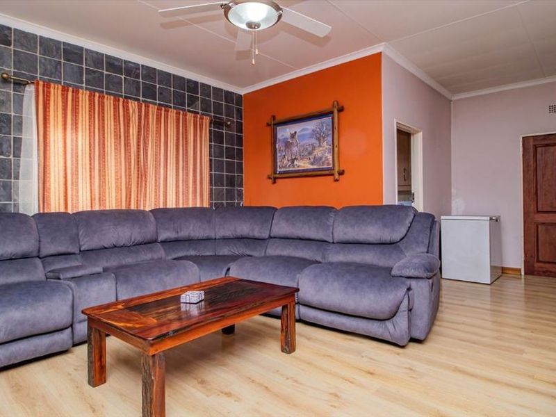 A living room featuring laminate flooring, a slate tile accent wall, and a ceiling fan, providing a functional and comfortable living space.
