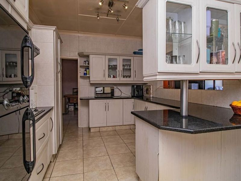 A functional kitchen featuring granite countertops, built-in oven, glass-front cabinetry, and tiled flooring, offering a classic layout with ample storage space.
