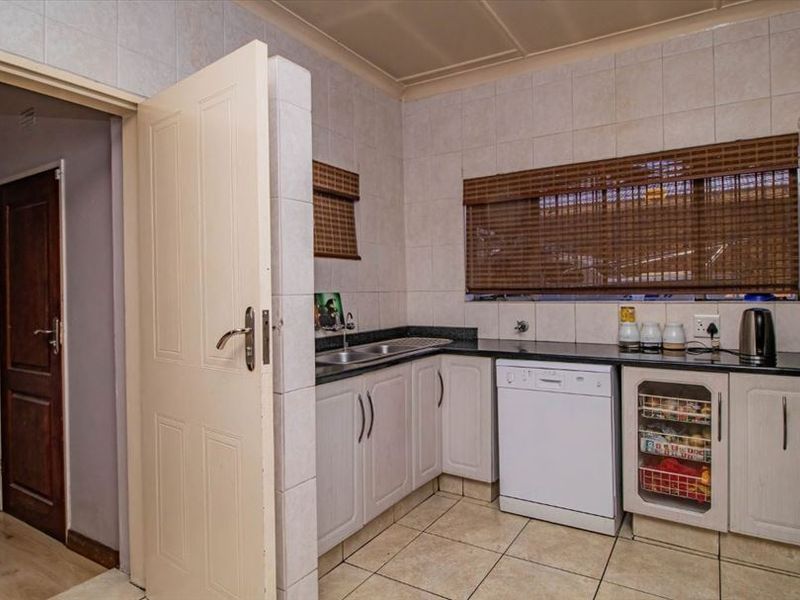 Functional kitchen featuring granite countertops, tiled backsplash, ample built-in cabinetry, and tiled flooring, providing a practical workspace for daily meal preparation.