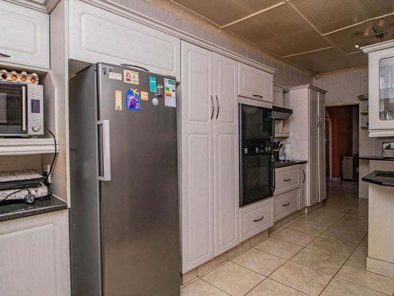A functional kitchen featuring light-toned built-in cabinetry, granite countertops, a built-in oven, and tiled flooring with a classic layout.