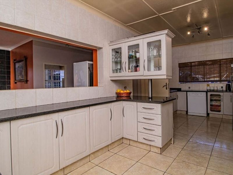 Functional kitchen featuring granite countertops, ample built-in cabinetry, glass-fronted display units, and a convenient pass-through window connecting to the adjacent living area.
