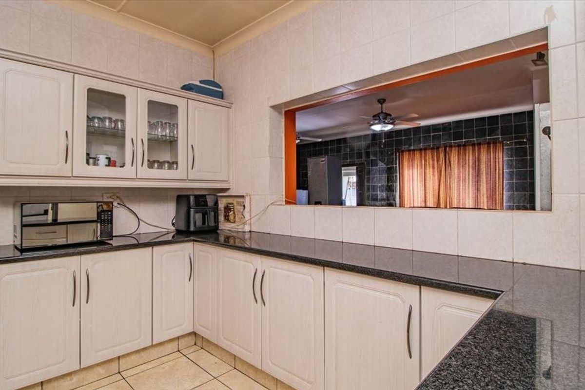 A functional kitchen featuring granite countertops, ample built-in cabinetry, and a convenient pass-through window connecting to the adjacent living space.