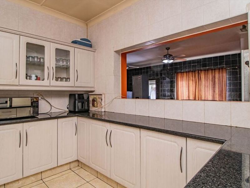 A functional kitchen featuring granite countertops, ample built-in cabinetry, and a convenient pass-through window connecting to the adjacent living space.