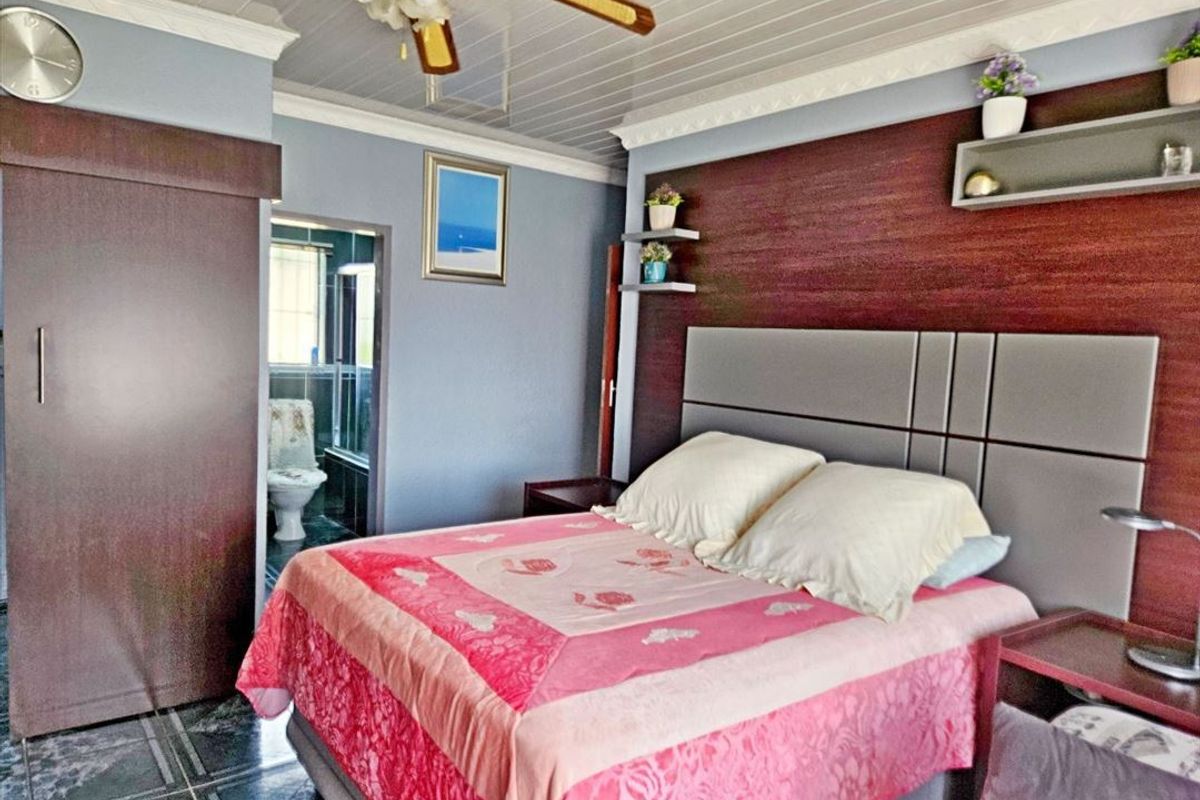 A bedroom featuring built-in cabinetry, a decorative ceiling fan, tiled flooring, and an adjoining en-suite bathroom.