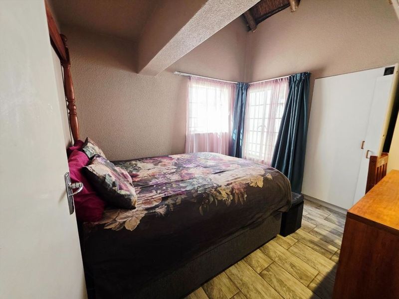 A bedroom featuring a vaulted ceiling, tiled flooring, and a built-in wardrobe, offering a cozy and functional living space.
