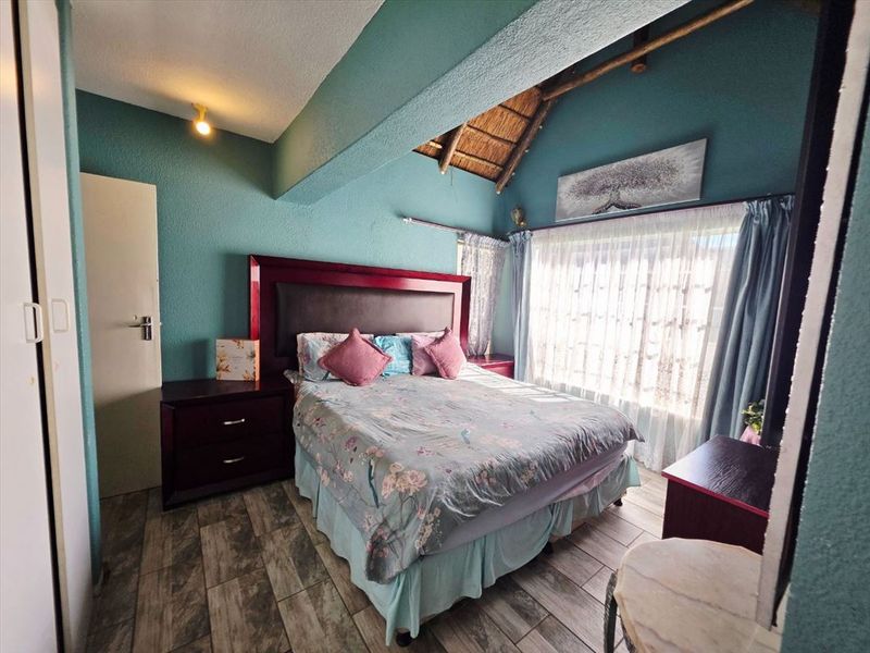 A bedroom featuring a unique thatched ceiling with exposed timber beams, tiled flooring, and a built-in cupboard.