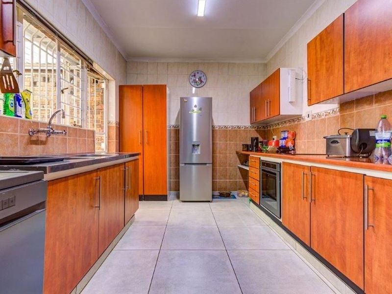 A functional kitchen featuring wood-finish cabinetry, tiled backsplash, built-in oven, and ample counter space with a stainless steel sink.