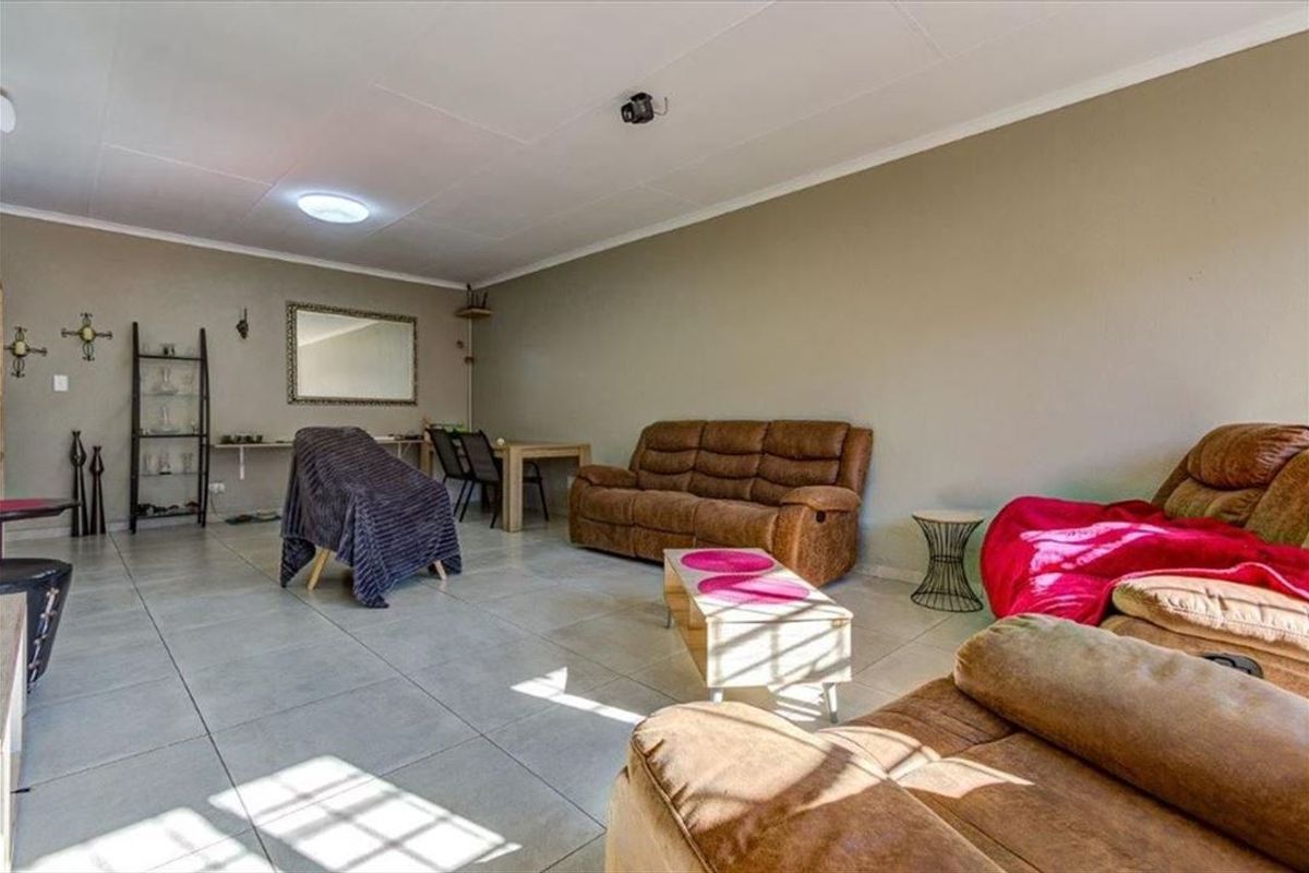 A spacious living room featuring neutral wall tones and large format floor tiles, offering a versatile layout for comfortable seating and dining arrangements.