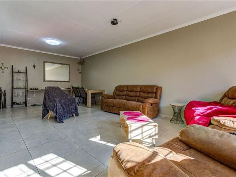 A spacious living room featuring neutral wall tones and large format floor tiles, offering a versatile layout for comfortable seating and dining arrangements.