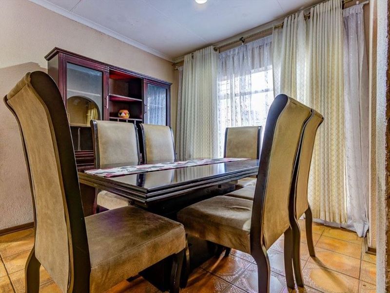 A dining room featuring ceramic tile flooring and an exposed brick wall accent, providing a traditional foundation for a formal dining space.