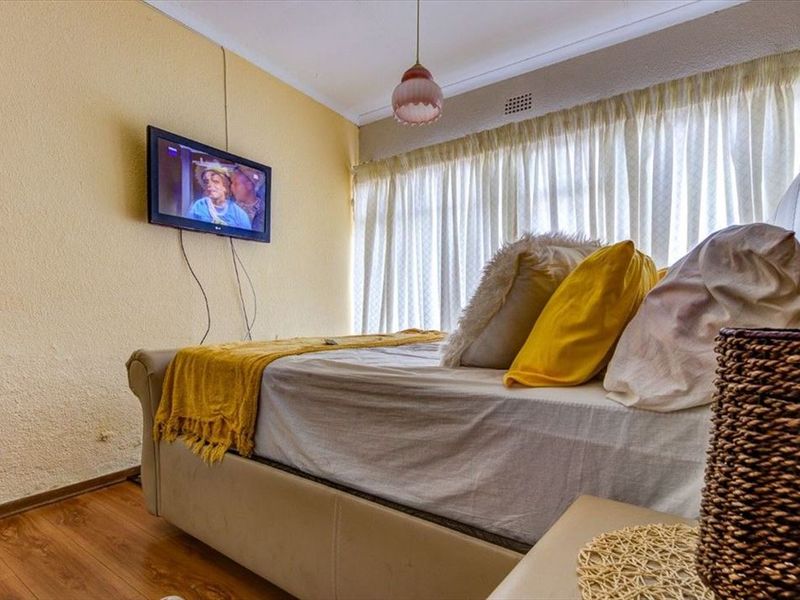 A bedroom featuring laminate flooring and textured walls, offering a functional space that could benefit from cosmetic updates.