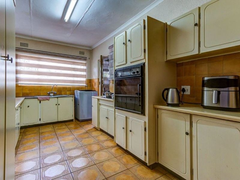 A dated kitchen featuring original cabinetry, tiled flooring, and a built-in oven, offering significant potential for a modern renovation and layout update.