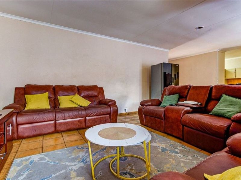 A spacious living room featuring tiled flooring and recessed lighting, offering a comfortable area for relaxation and family gatherings.