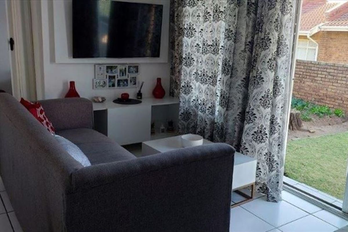 A living room featuring tiled flooring and a sliding glass door providing direct access to the rear garden area.