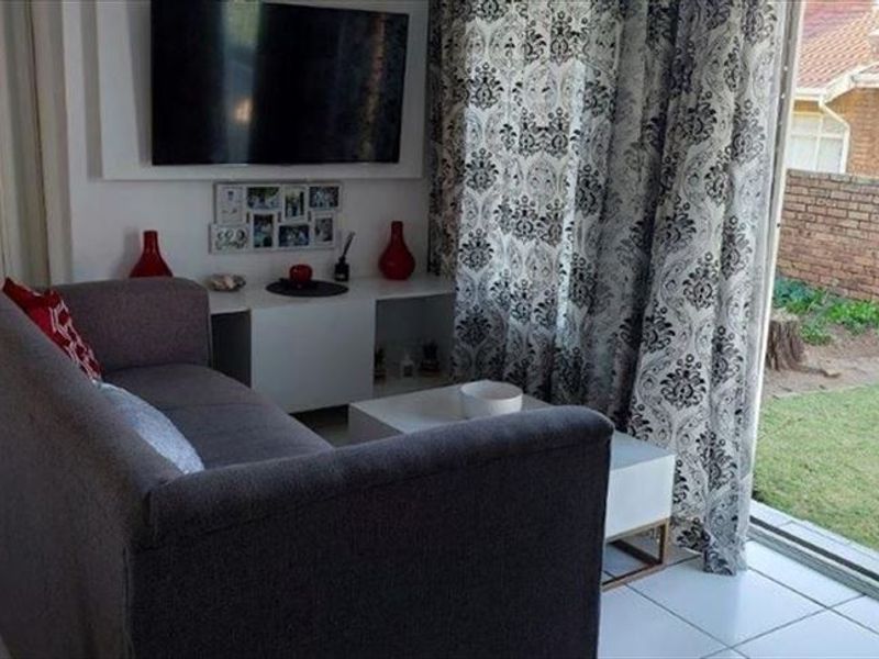 A living room featuring tiled flooring and a sliding glass door providing direct access to the rear garden area.