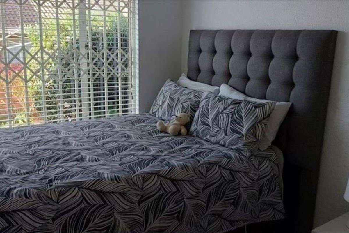 A bedroom featuring a large window with an integrated security gate, providing natural light and security.