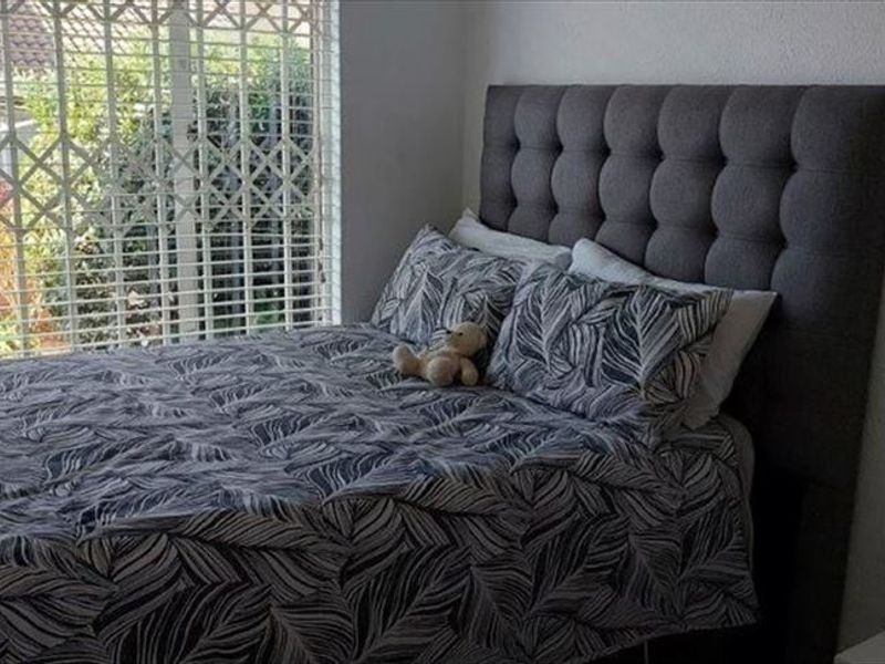 A bedroom featuring a large window with an integrated security gate, providing natural light and security.