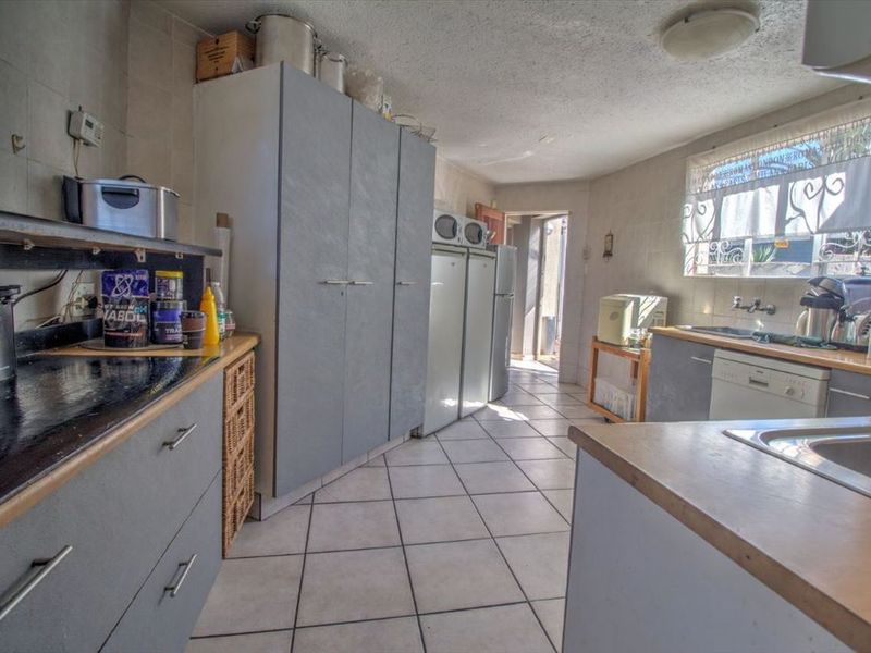 A functional kitchen featuring extensive built-in cabinetry, laminate countertops, and tiled flooring, offering a practical layout with potential for modern updates.