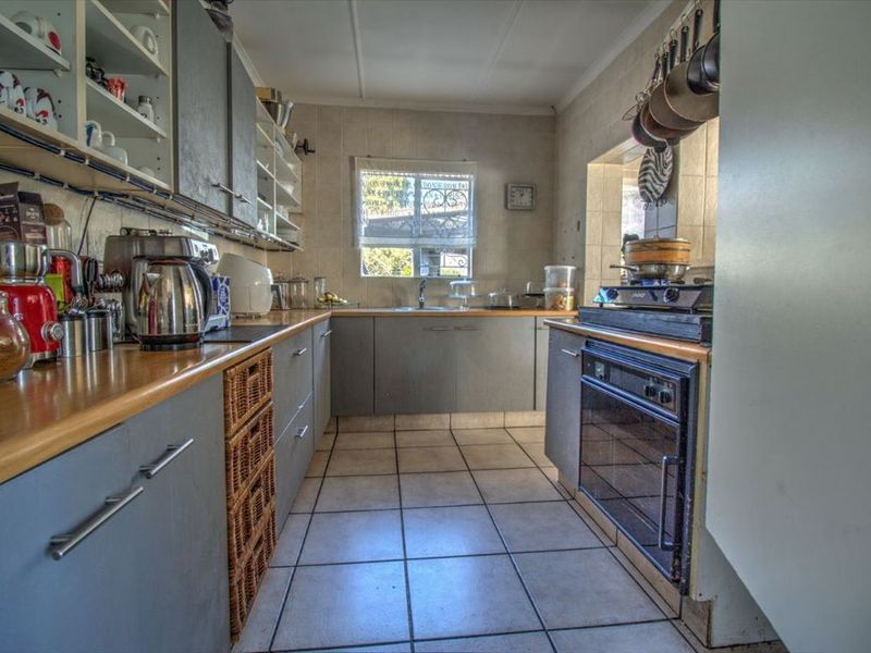 Functional kitchen featuring grey cabinetry, laminate countertops, built-in oven, gas hob, and tiled flooring with a practical layout.