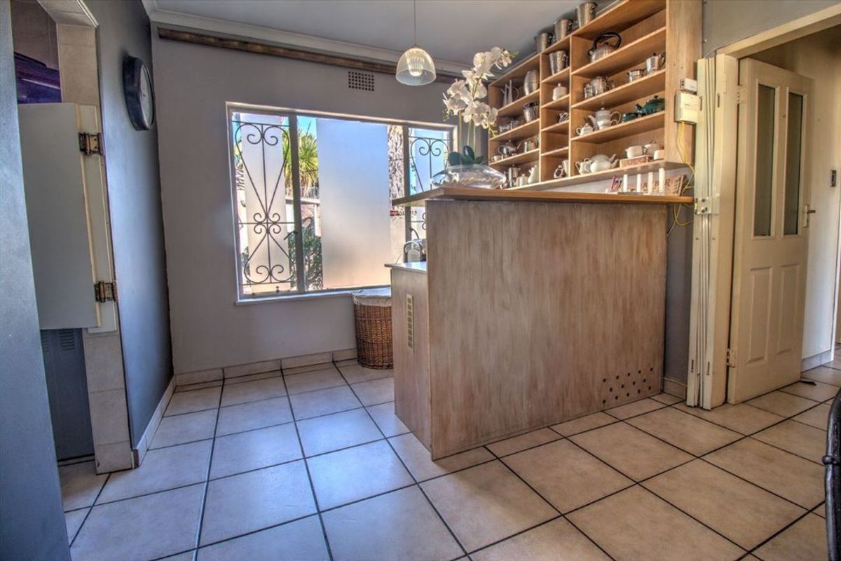 A kitchen area featuring tiled flooring, a built-in breakfast bar, and extensive open shelving for storage.