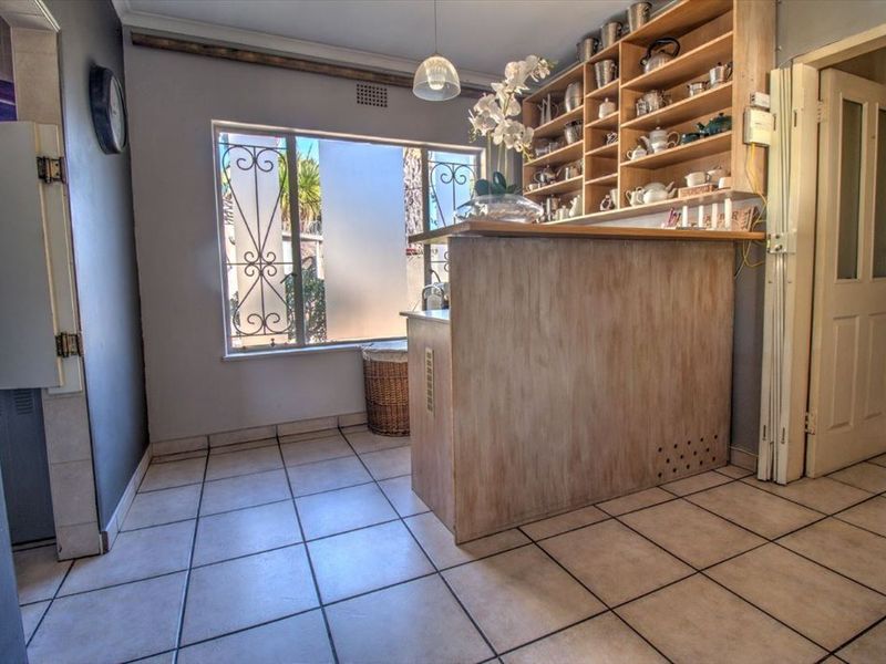 A kitchen area featuring tiled flooring, a built-in breakfast bar, and extensive open shelving for storage.