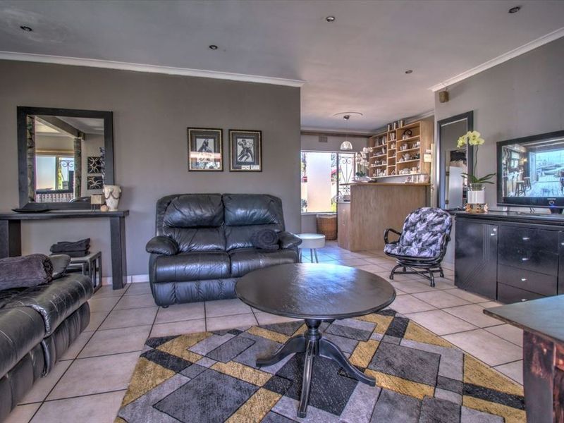 Open plan living area featuring tiled flooring, recessed lighting, and a built-in bar area with shelving.